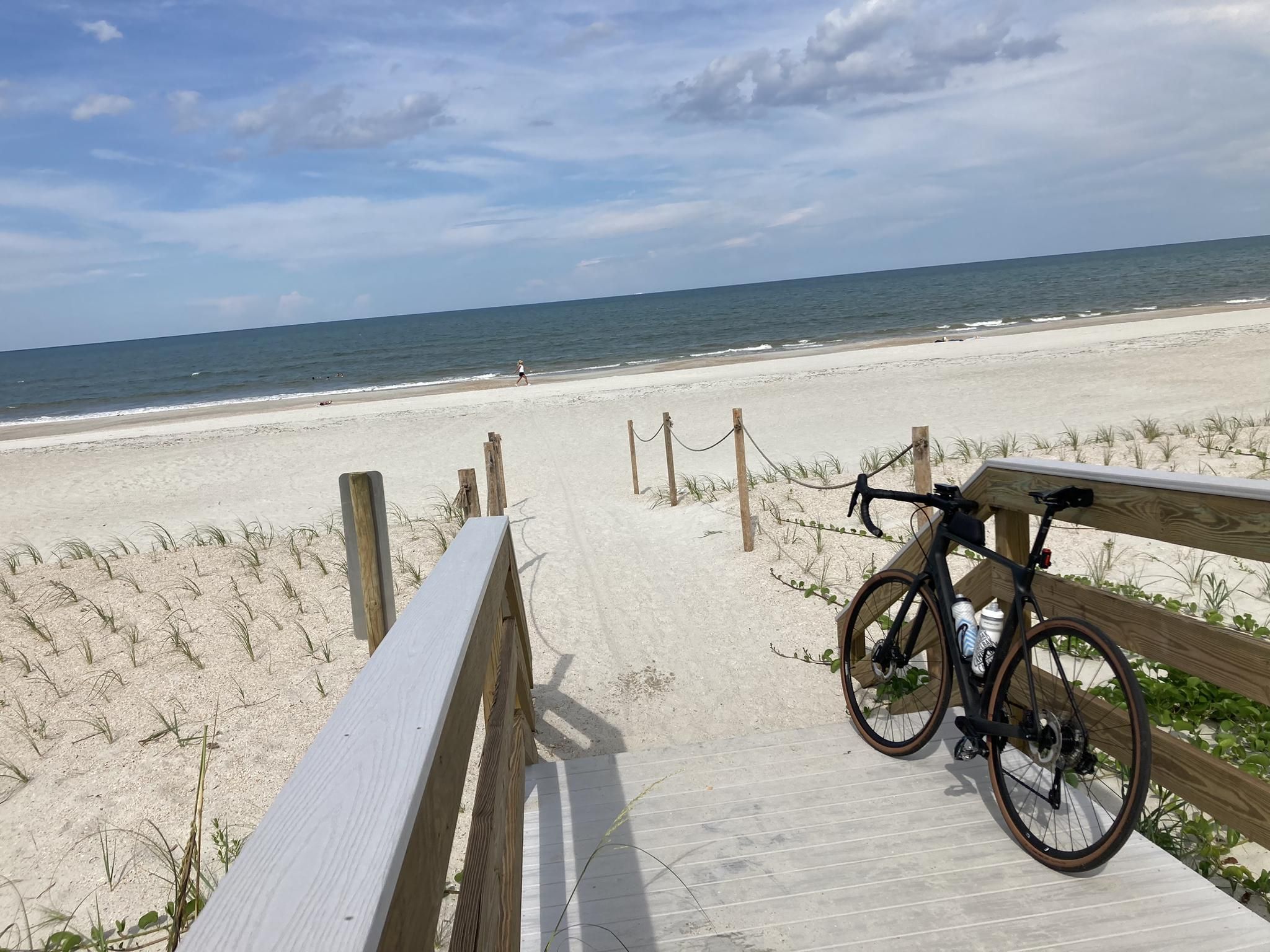 Bicycle parked on a wooden boardwalk overlooking a wide sandy beach and ocean. - Jacksonville Beaches - East Coast Greenway Loop