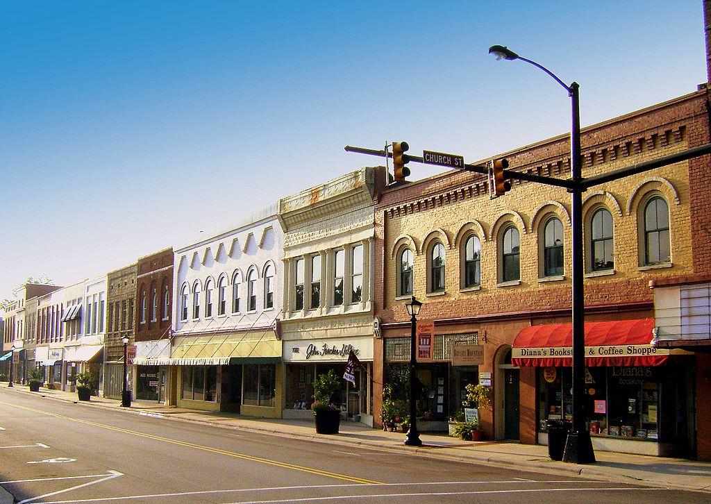 A sunny street lined with historic brick and stone buildings under a clear sky.
