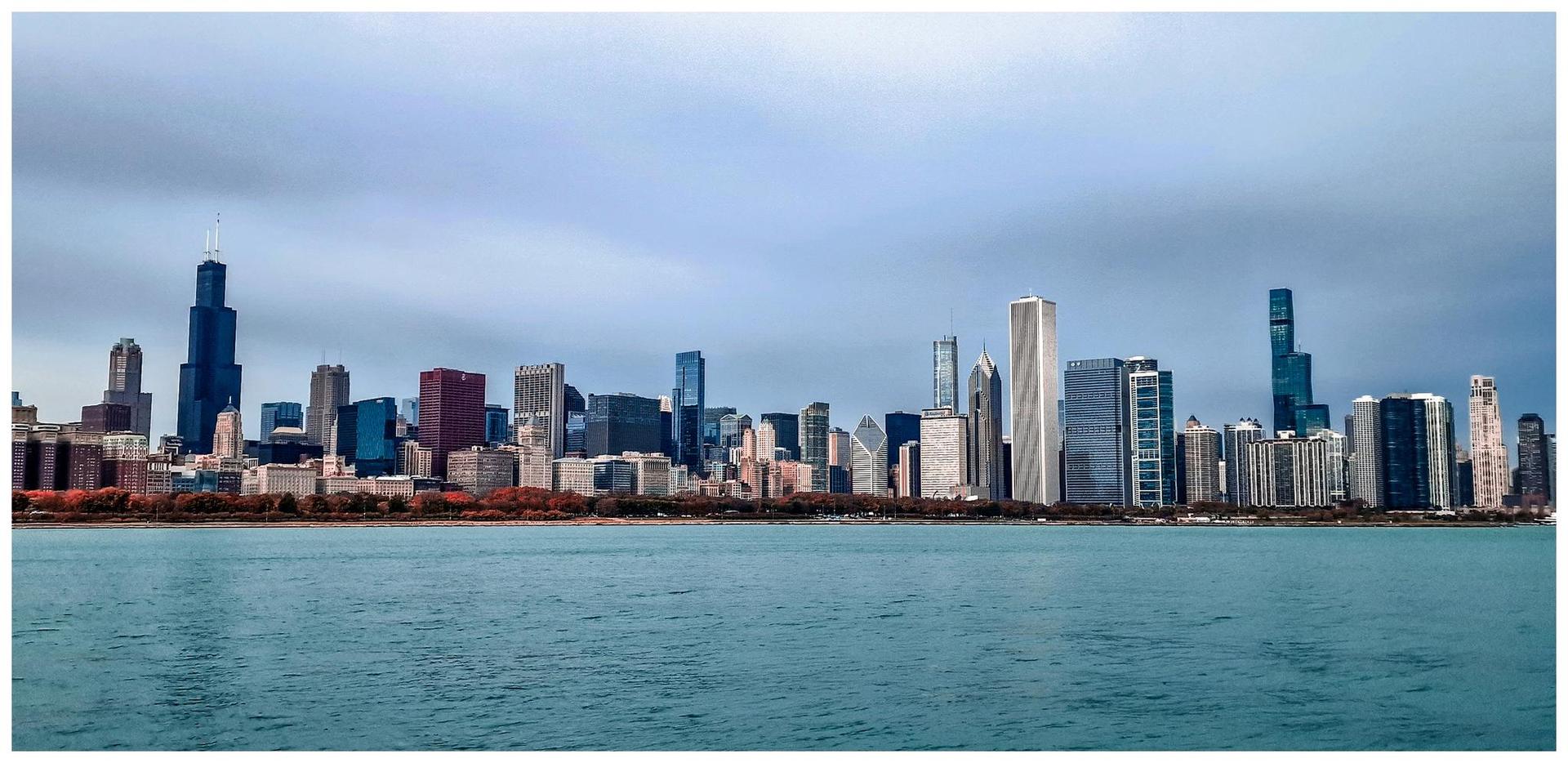 Distant city skyline across a wide body of water under a cloudy sky.