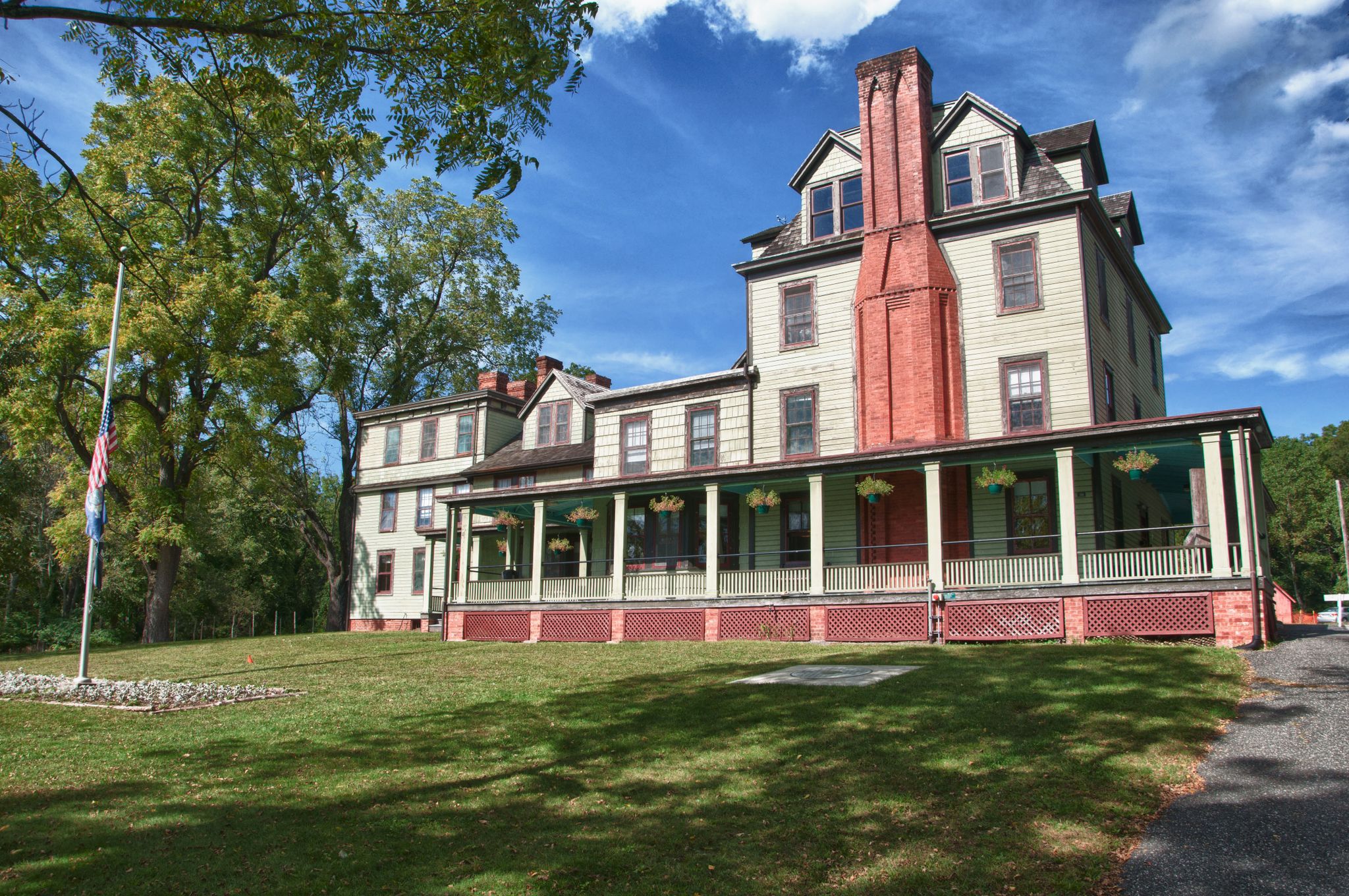 Large historic building with a long porch and flagpole on a sunny day. - Green Trail