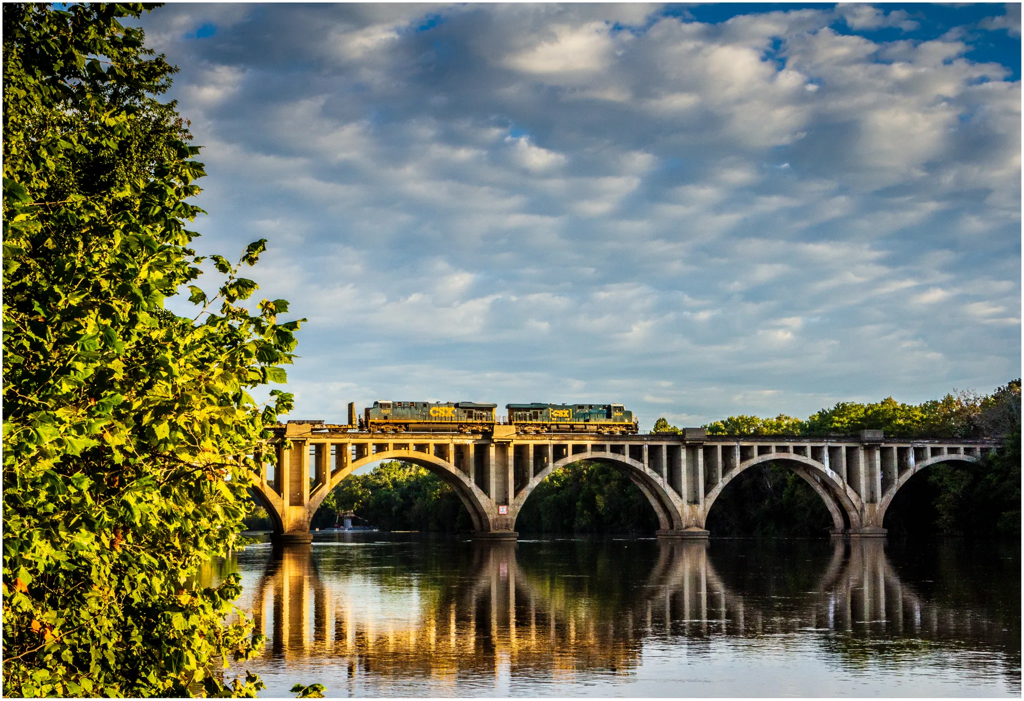 Train crossing an arched bridge over a river with golden reflections. - Falmouth Beach Park loop from Falmouth