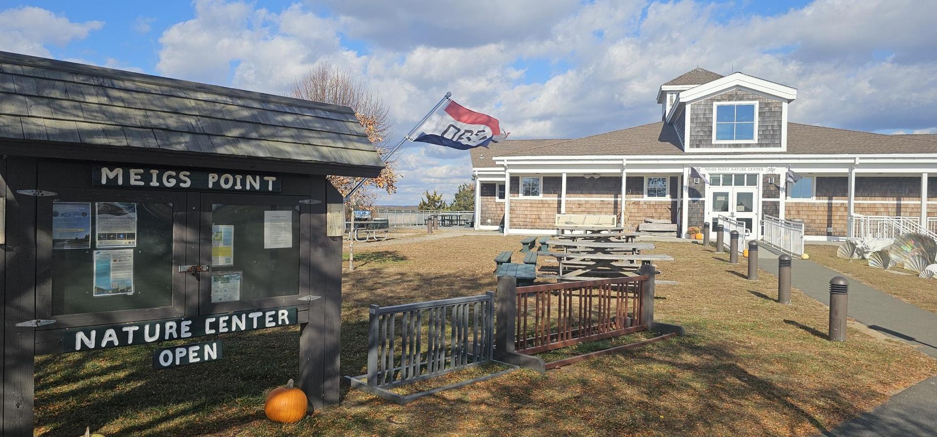 Information kiosk and building with flag under a partly cloudy sky.