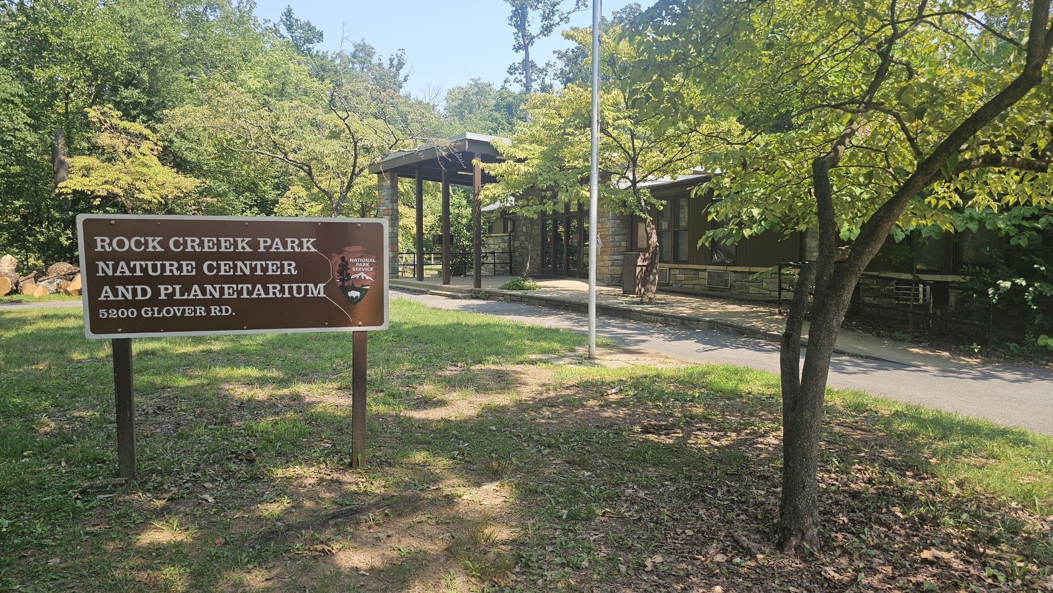 Wooden sign in front of a nature center building on a sunny day. - Milkhouse Ford Loop
