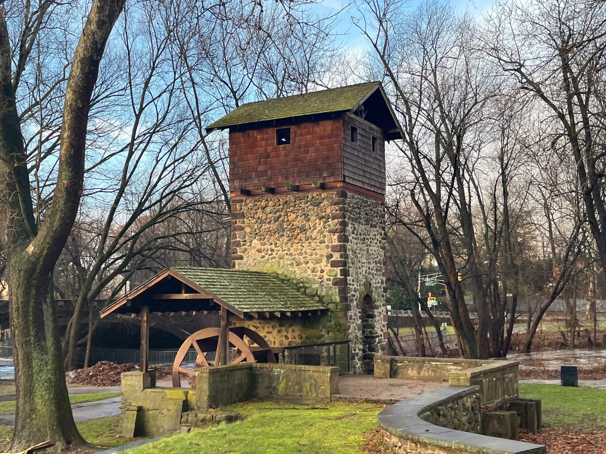 A stone and wood building with a water wheel among bare trees. - Saddle River loop from Saddle Brook