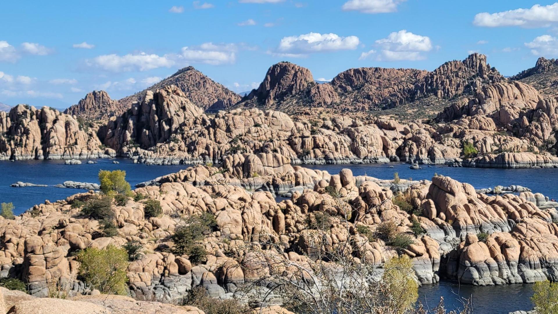 Expansive view of a lake surrounded by dramatic, eroded rock formations and mountains.