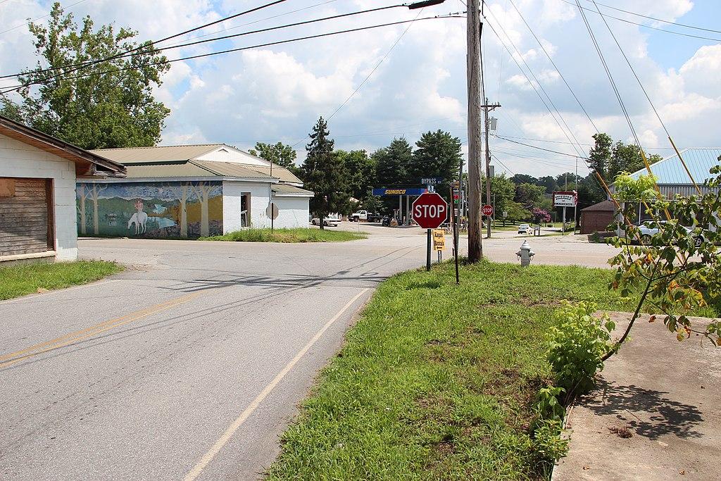 A rural intersection with a stop sign and small buildings on a sunny day.
