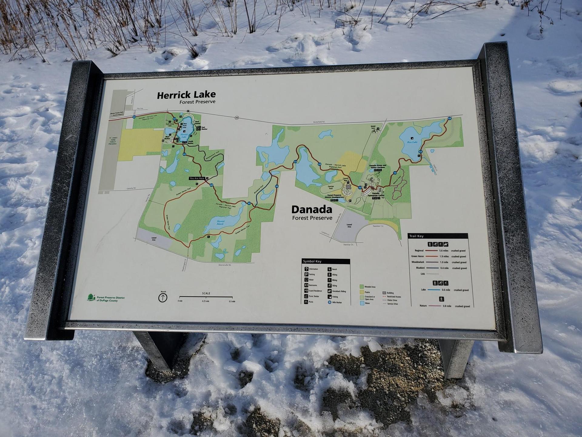 A park map display stands in snow on a bright winter day.