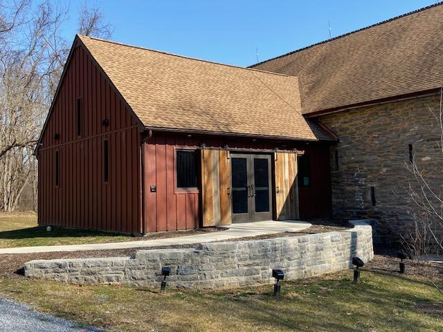 A red barn-style building with a stone wall under a bright blue sky.