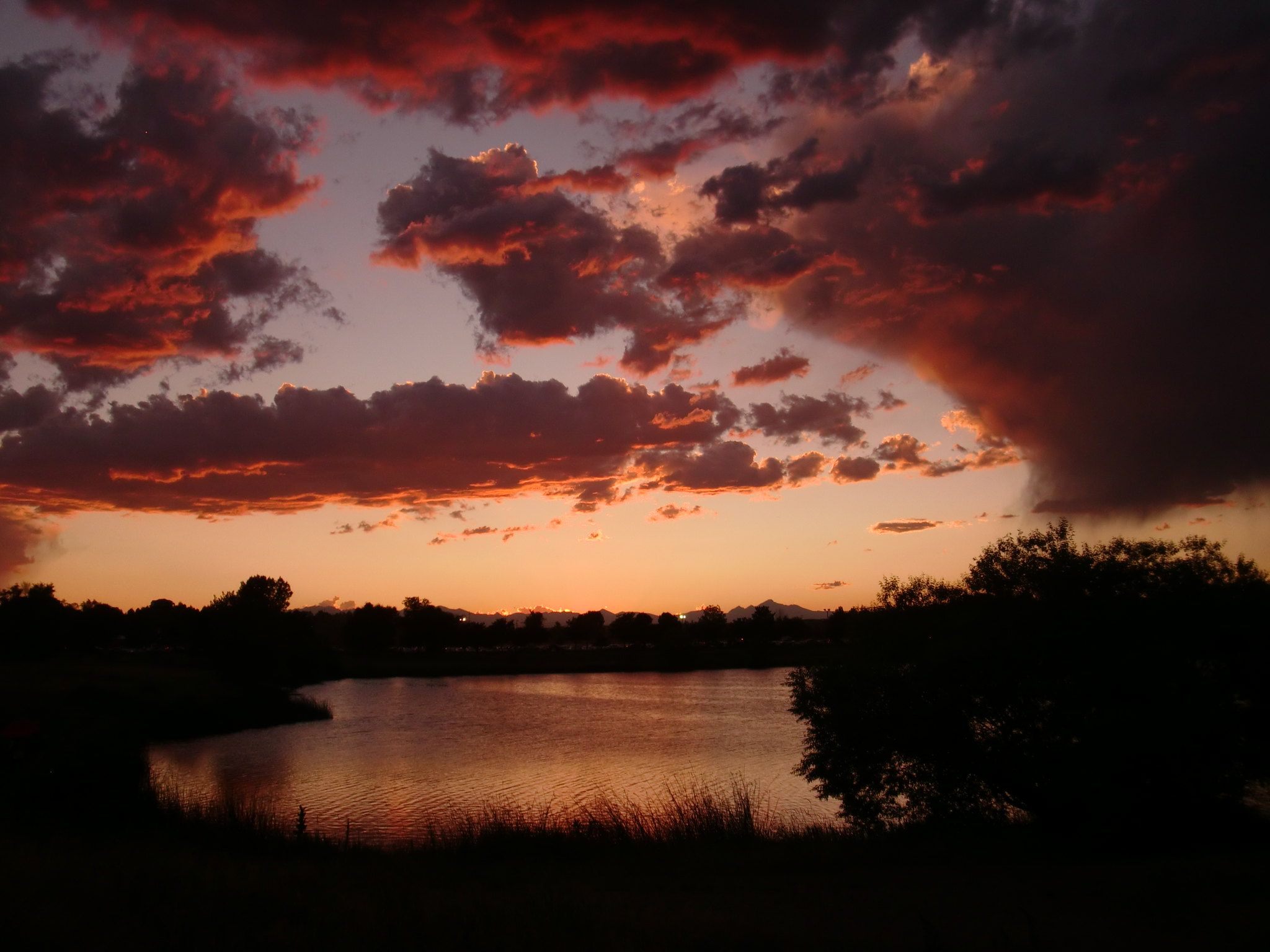 Dramatic sunset over a dark lake with fiery orange and red clouds. - Riverdale Regional Park Loop