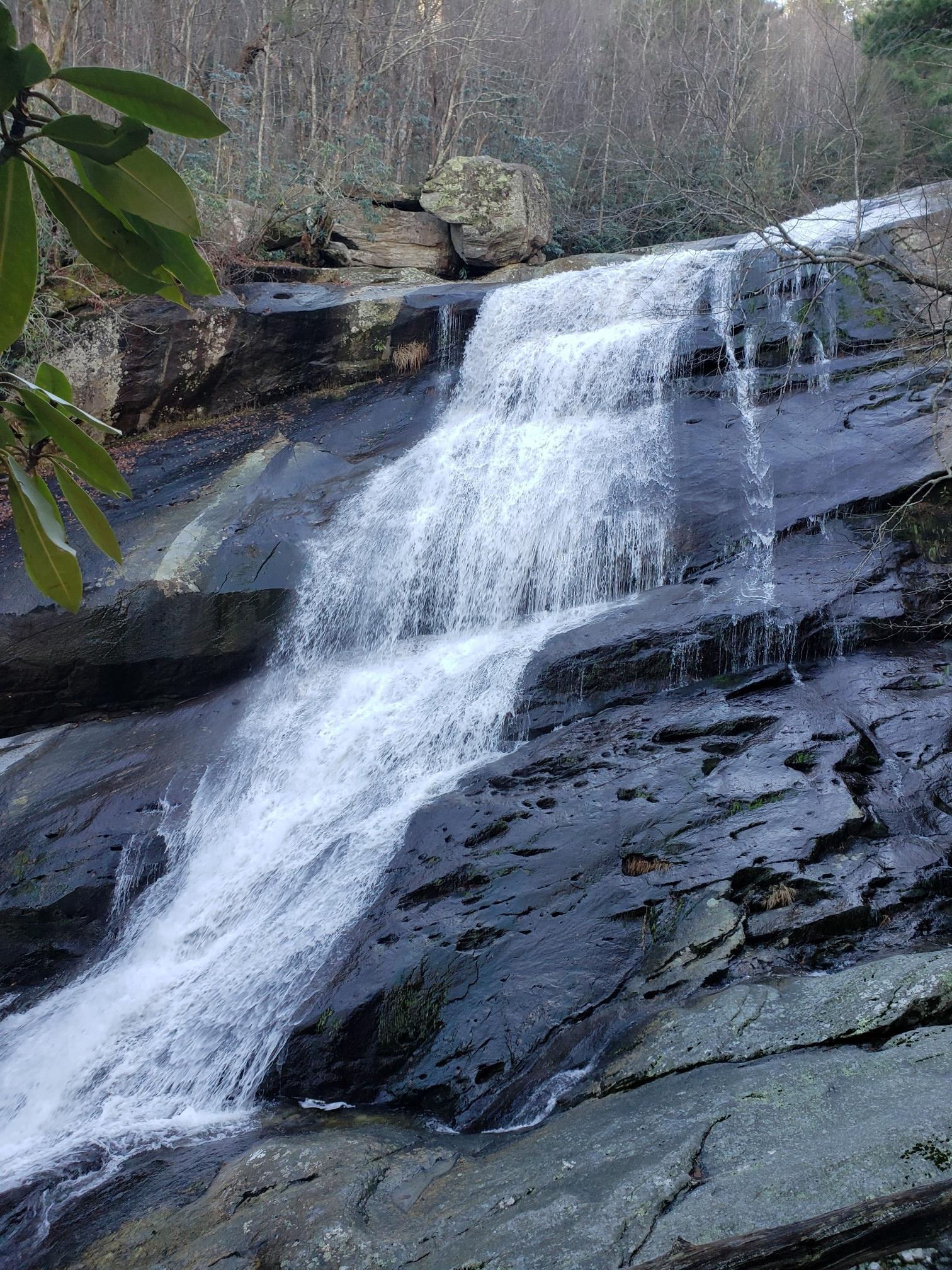 Beautiful waterfall cascading over dark, wet rocks in a lush forest.