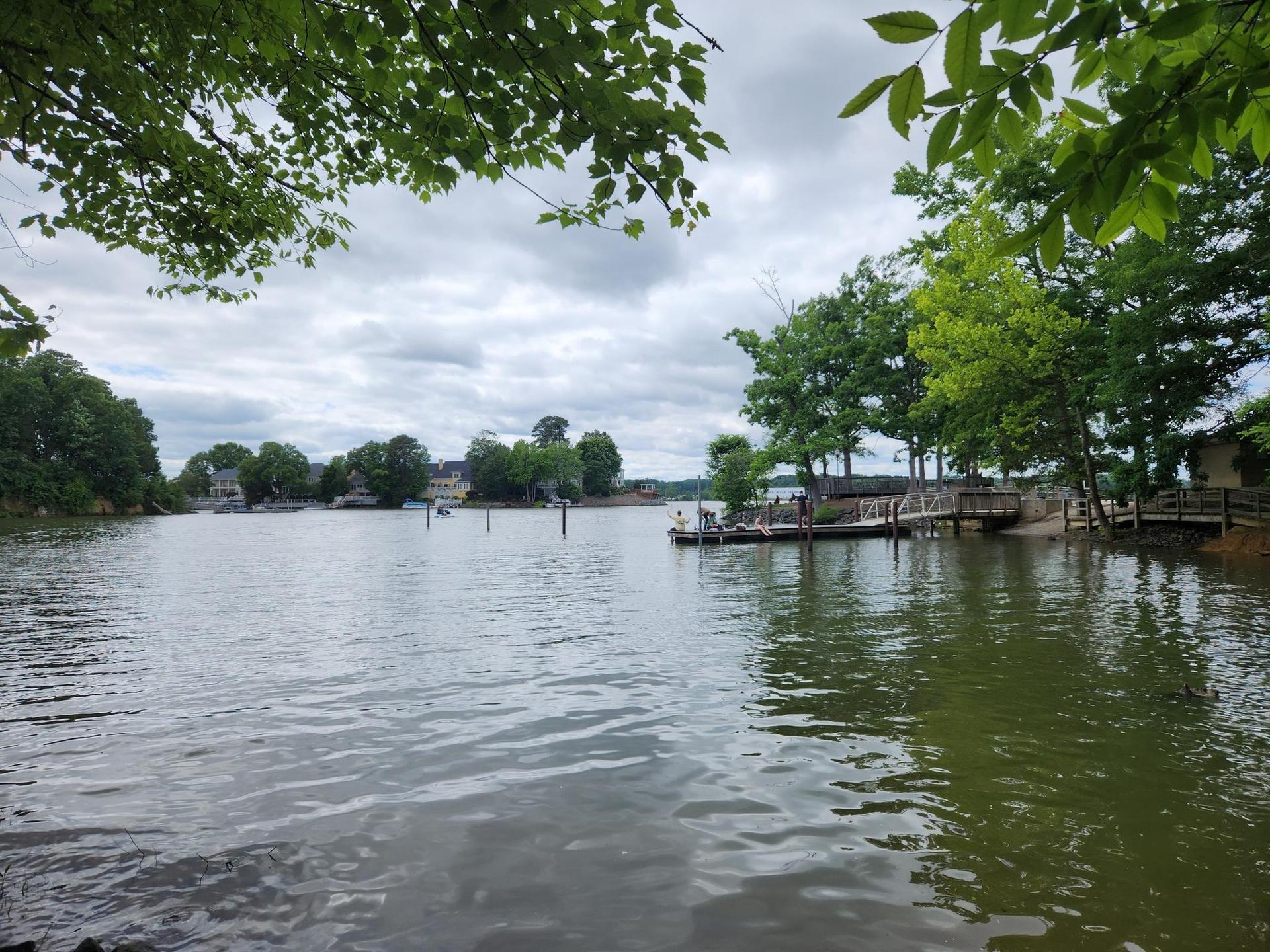 Overcast view of a wide lake with docks, boats, and green trees along the shore.