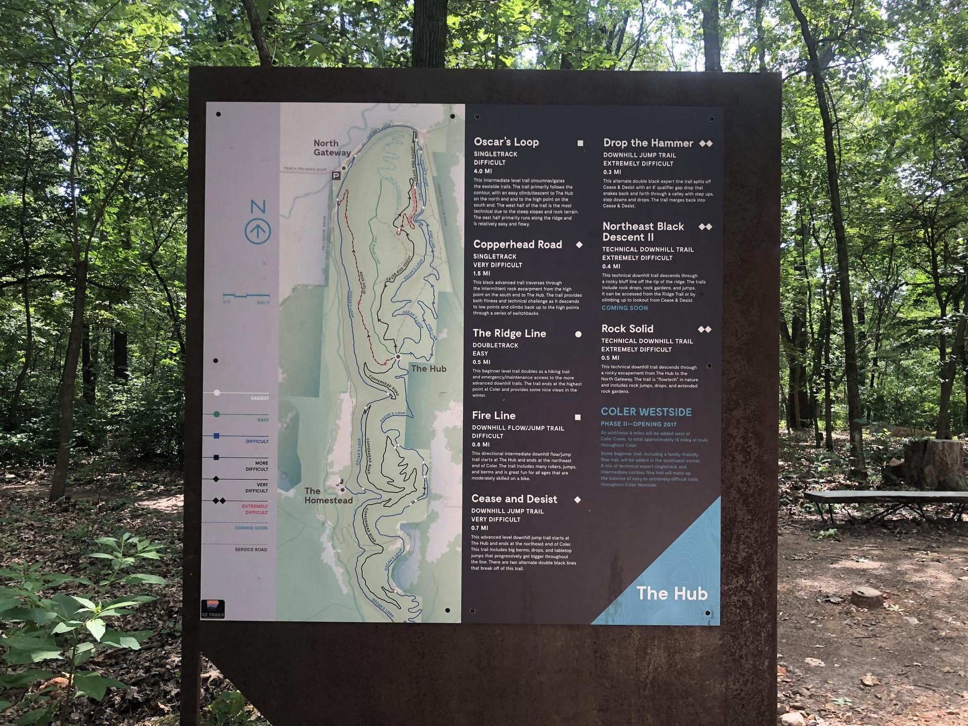 Large information sign with a map and text in a green forest.