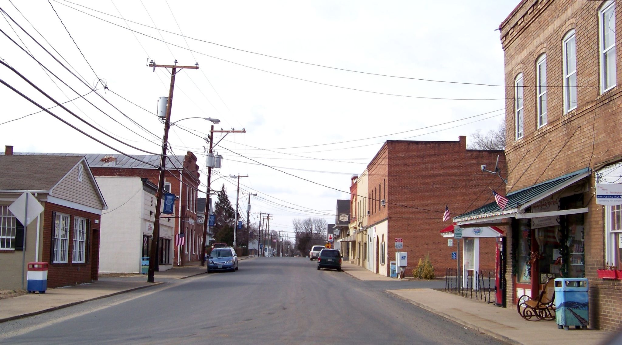 Empty small town street with brick buildings and utility poles under a bright sky. - War House Museum – Main Street Remington loop from Remington