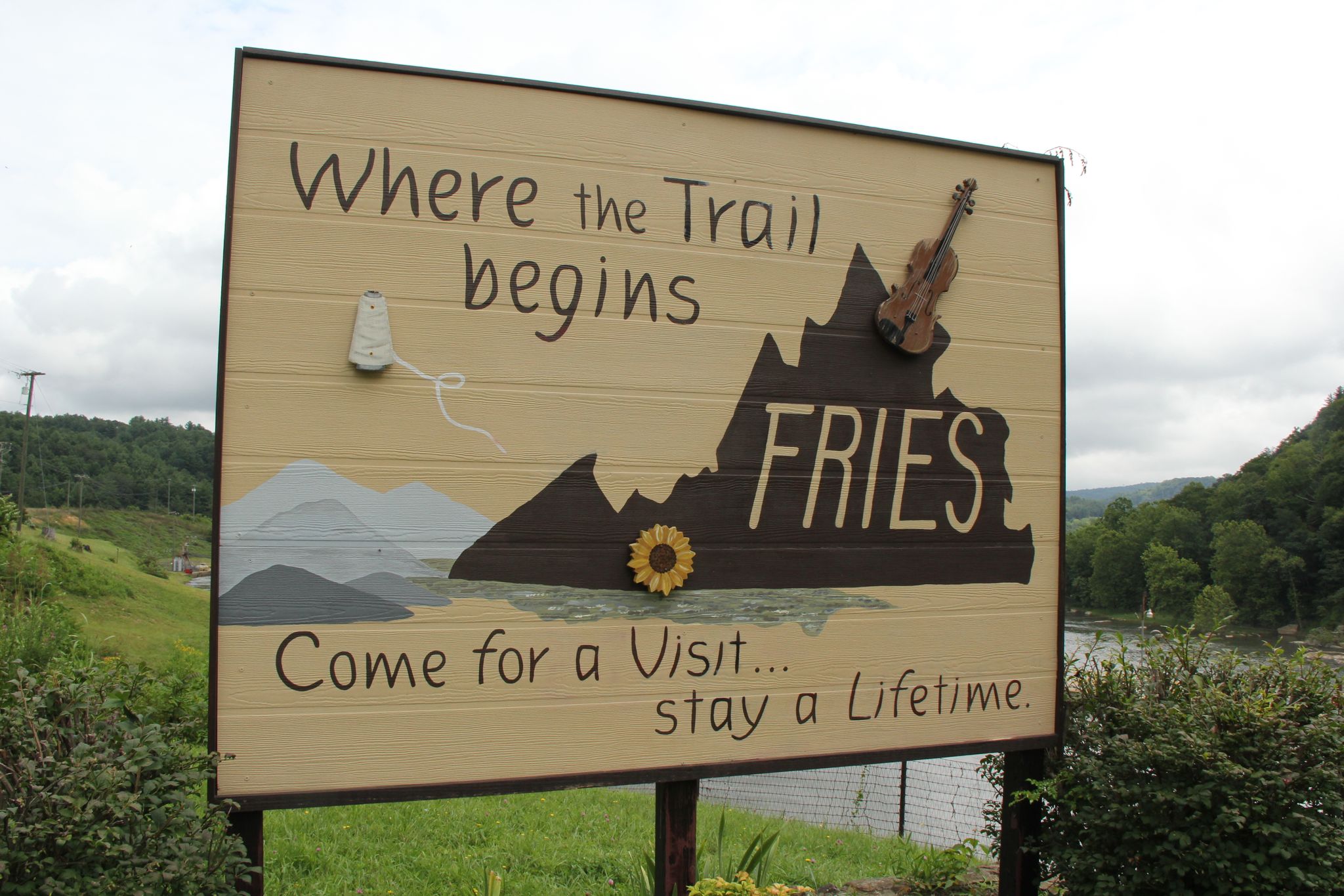 Large wooden sign with text, mountains, and a violin under a cloudy sky. - Galax to Fries loop