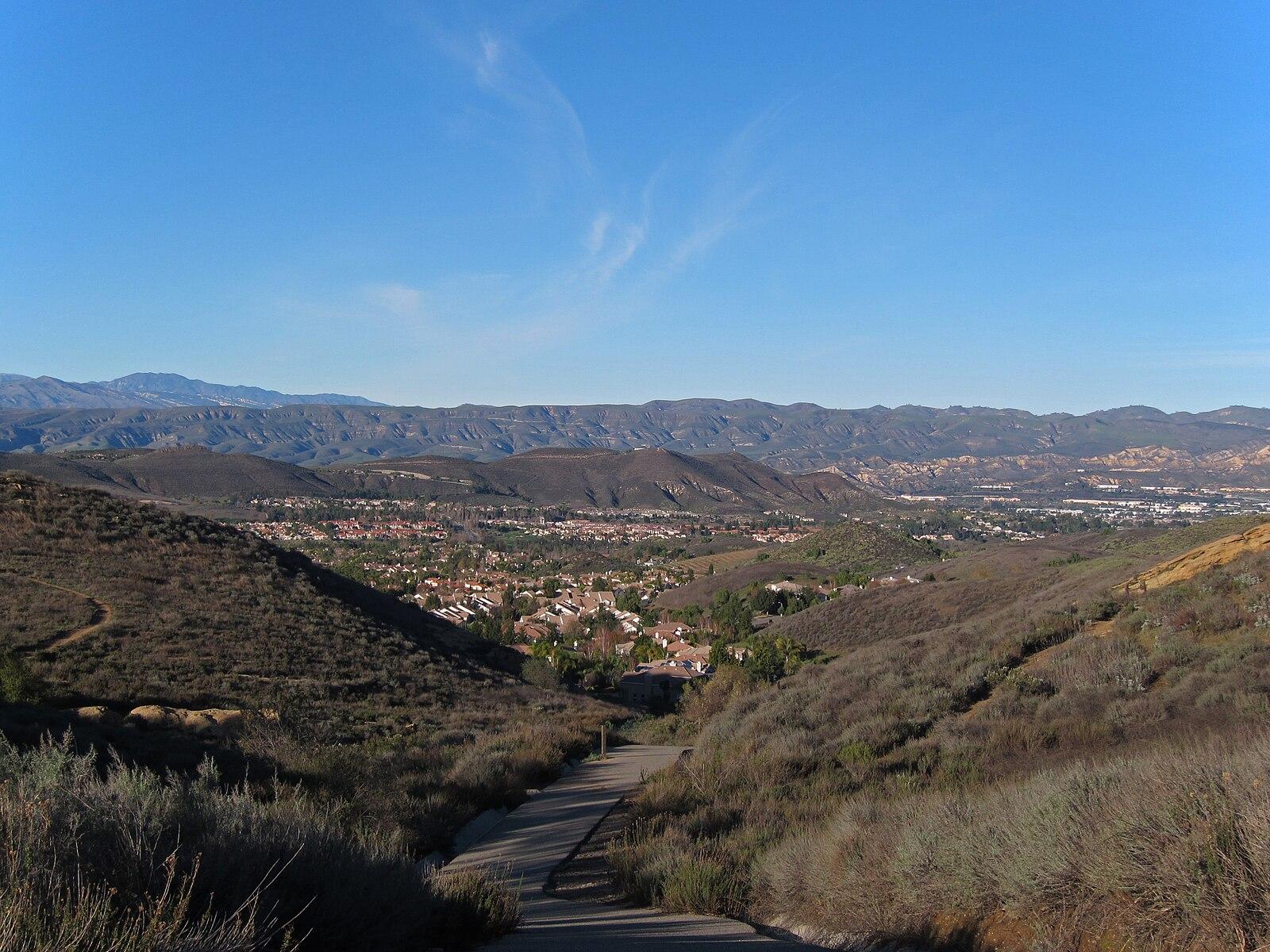 Panoramic view of a town nestled in a valley, surrounded by dry hills and mountains.