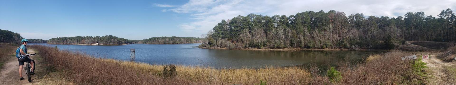 Panoramic view of a large lake with a person standing by a bicycle.