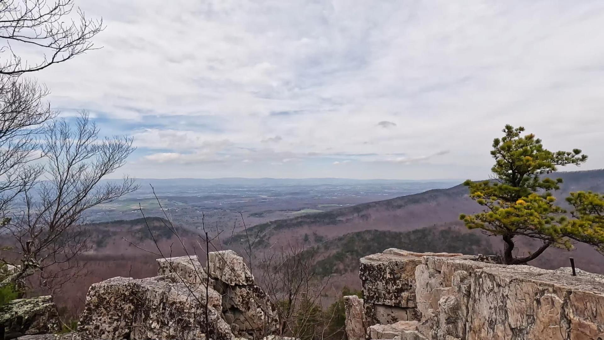 Overcast mountain view over rocky ledges and bare winter forests.