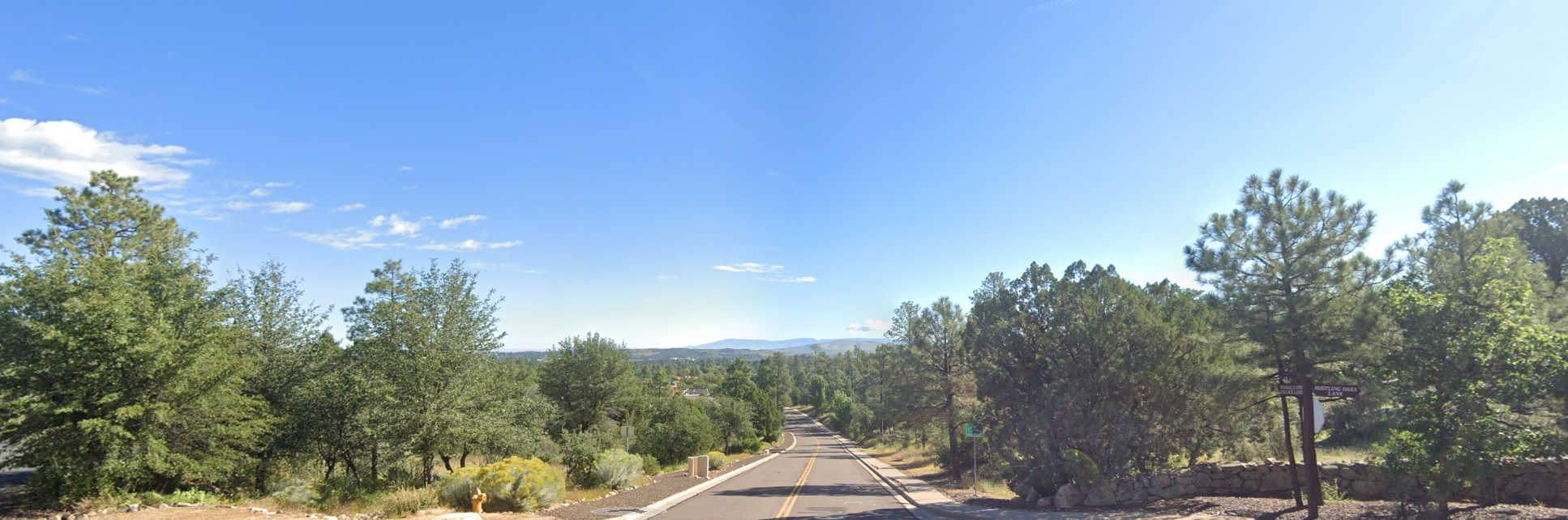 Paved road winding through a dense green forest under a clear blue sky. - Prescott Lakes Parkway loop via North Montezuma Street
