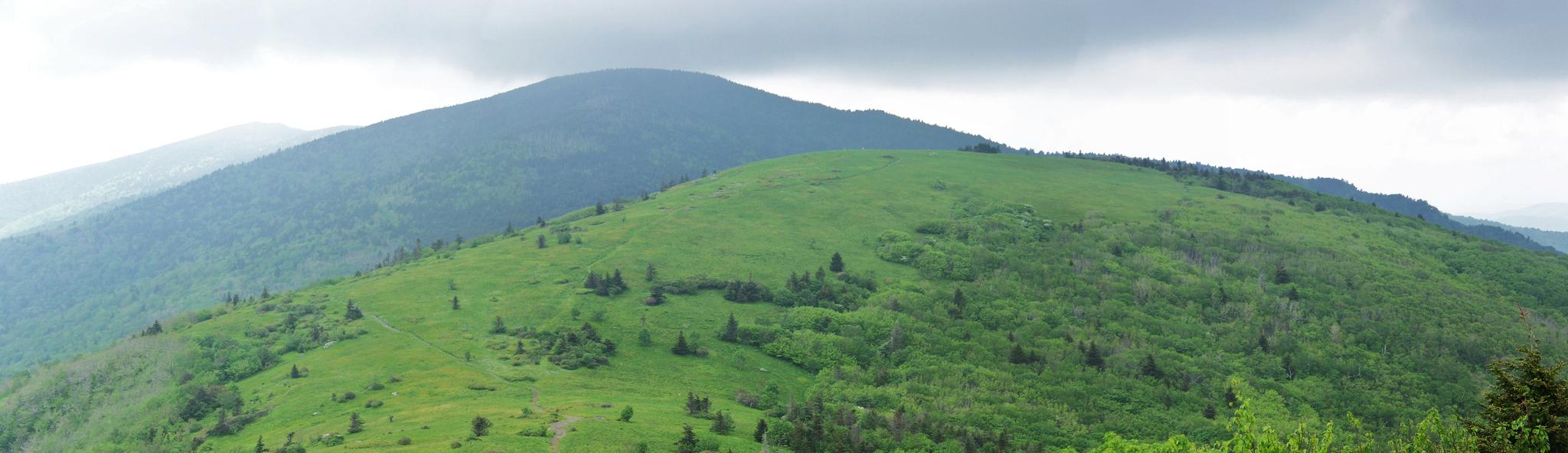 Panoramic view of rolling green mountains under a cloudy, overcast sky.