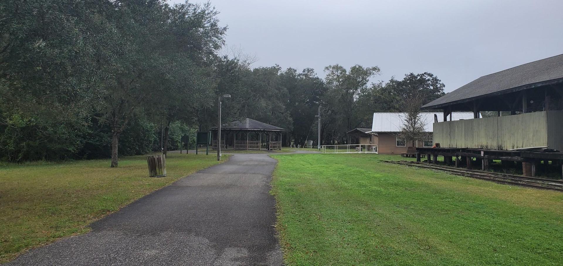 Paved path leading to a distant pavilion under an overcast sky.
