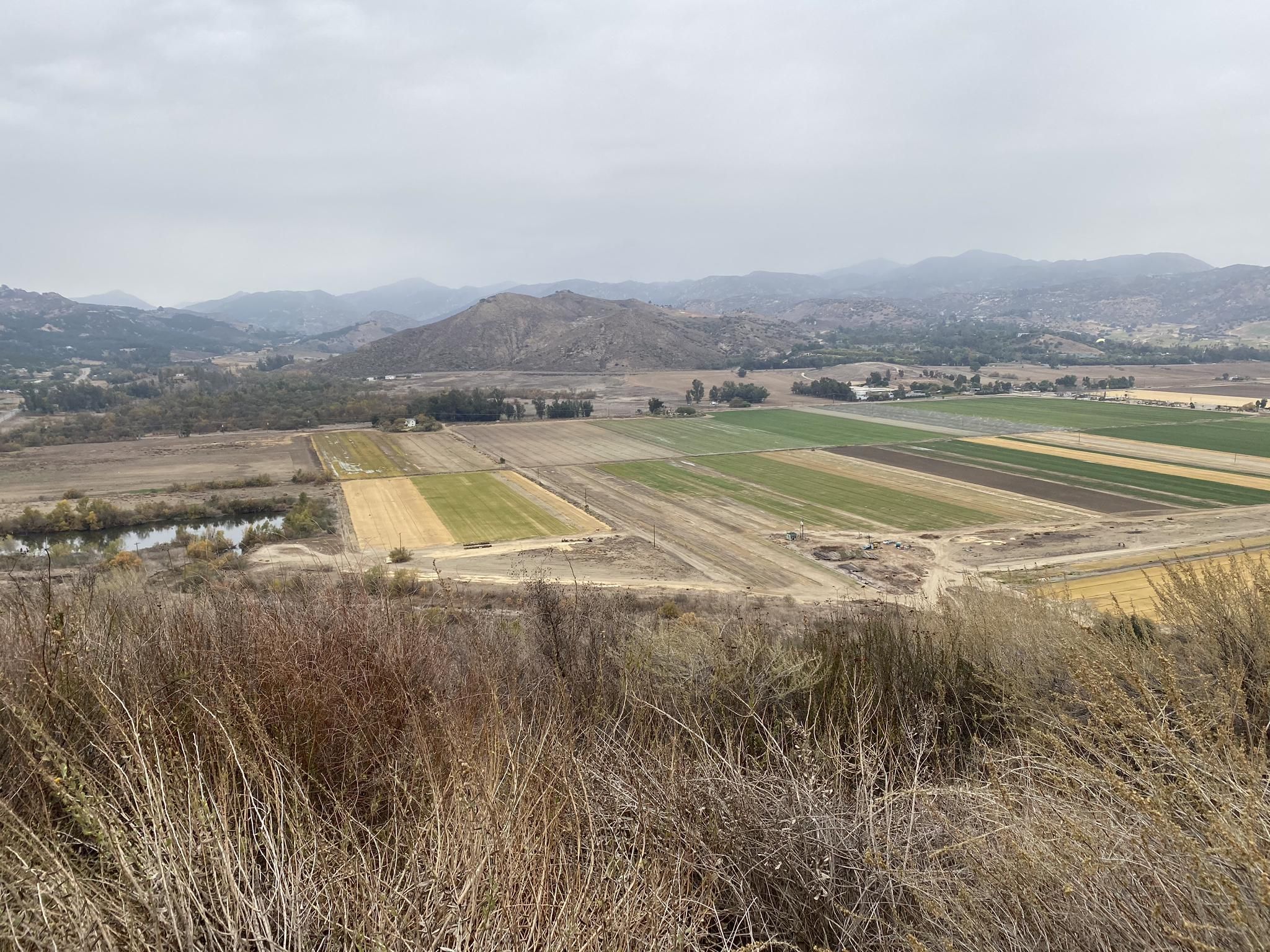 Overcast view of a valley with diverse agricultural fields and distant hills. - Raptor Ridge Viewpoint loop from San Pasqual