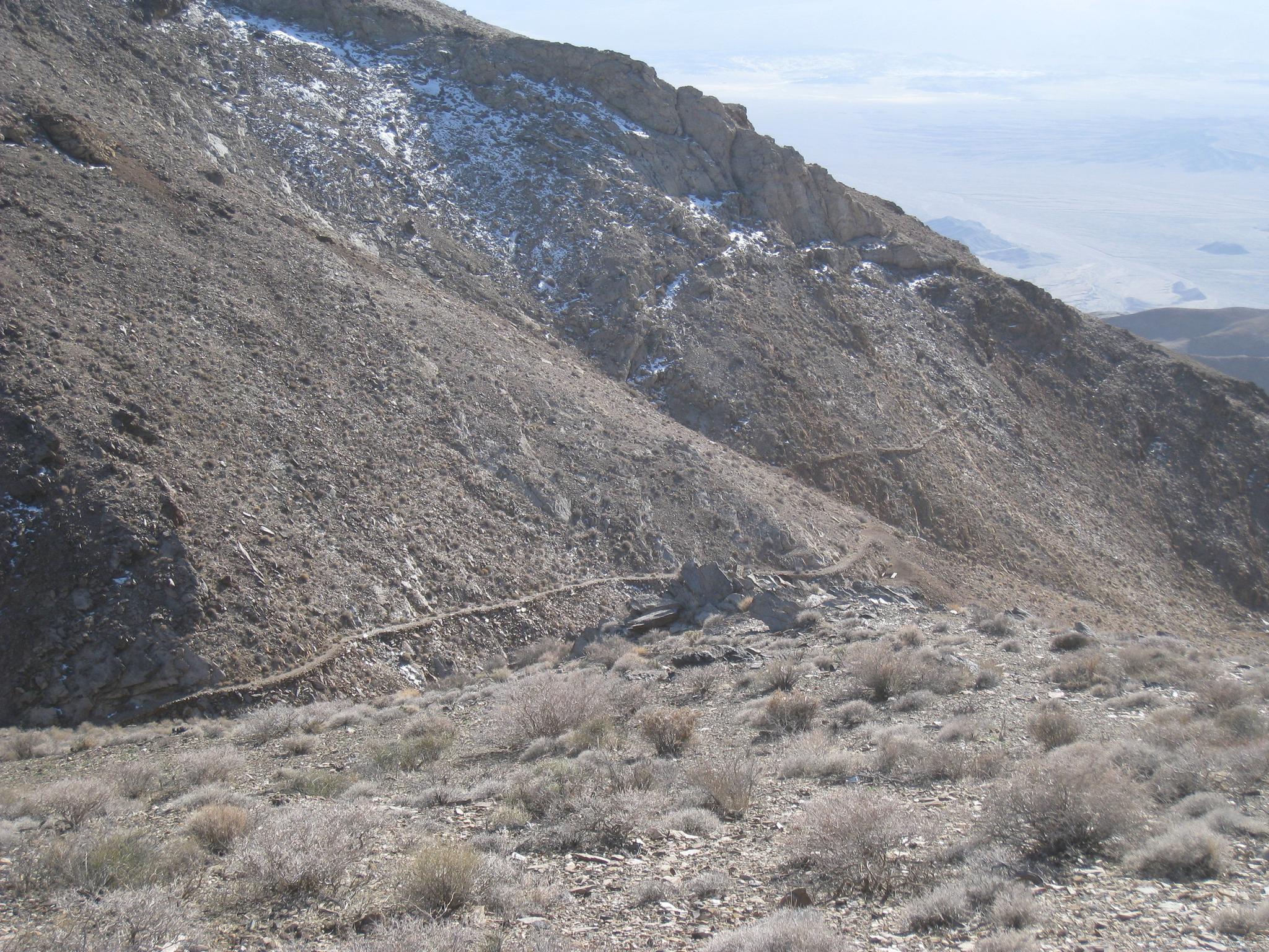 Steep, rocky mountain slope with a winding path and sparse vegetation.