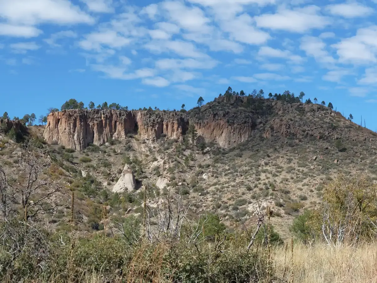 Distant mesa with cliff dwellings and sparse vegetation under a blue sky.