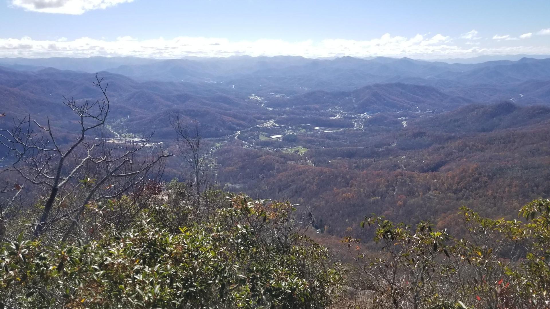Panoramic view of a vast mountain range and valley under a bright sky.