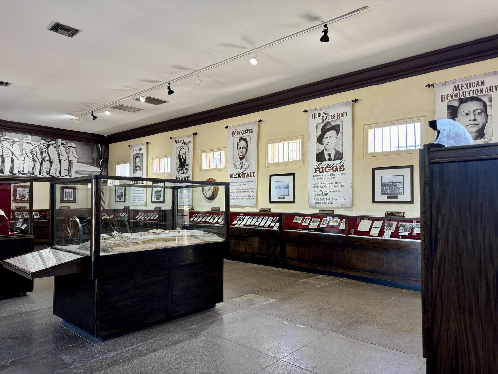 Museum interior with display cases, historical banners, and portraits on the walls.