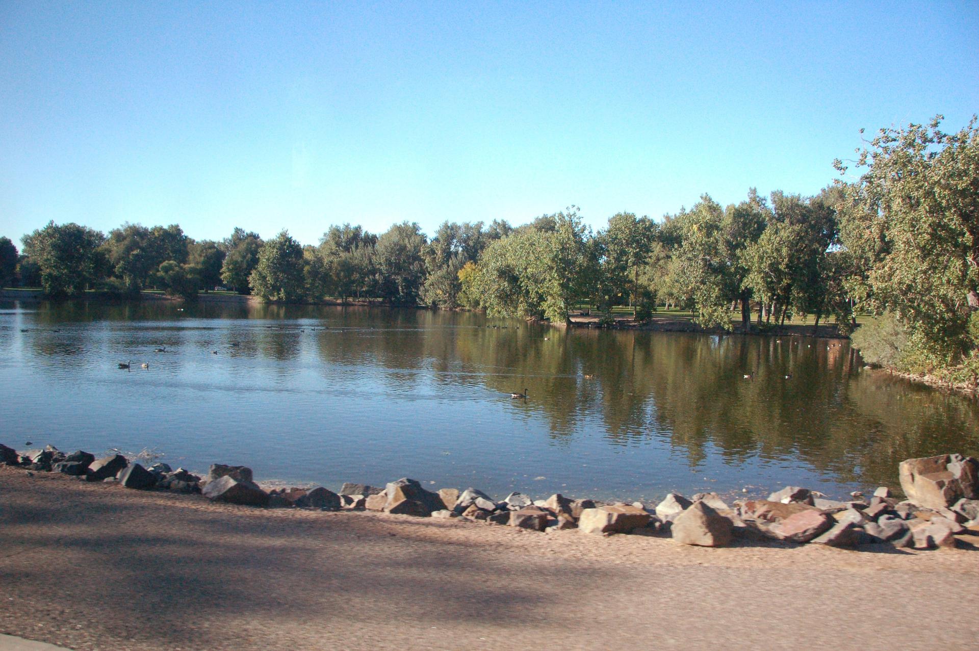 Calm lake with green trees reflecting in the water on a clear day.