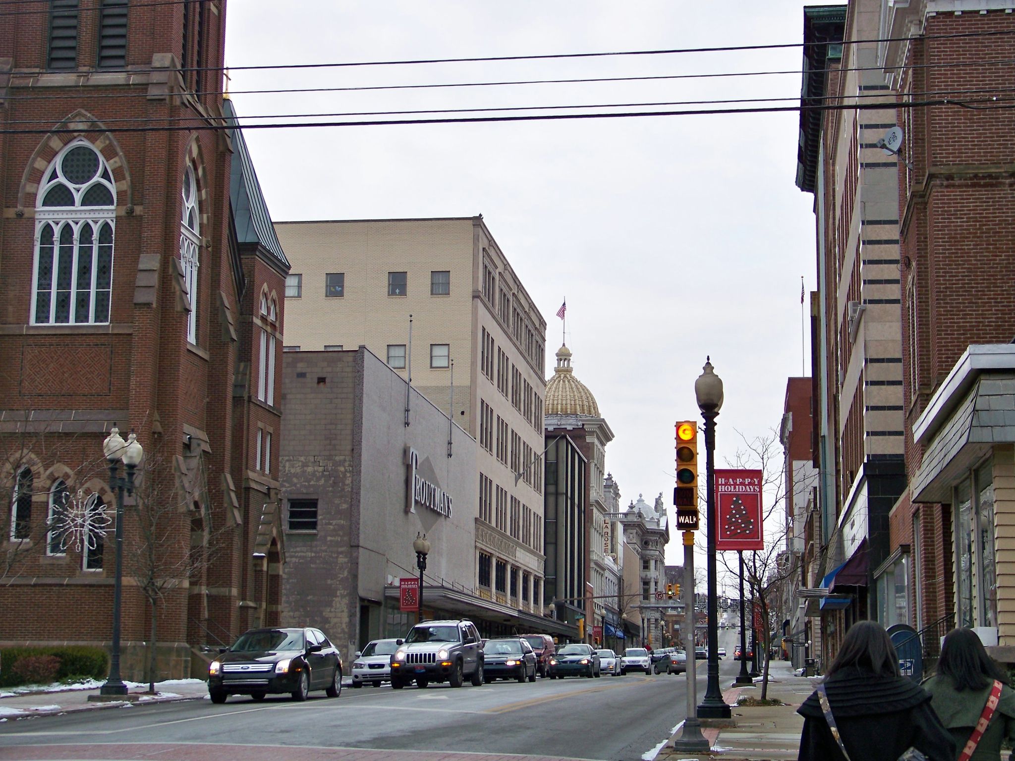 Overcast city street with historic buildings, moving cars, and pedestrians on sidewalk. - Greensburg – Five Star Trail loop from Greensburg