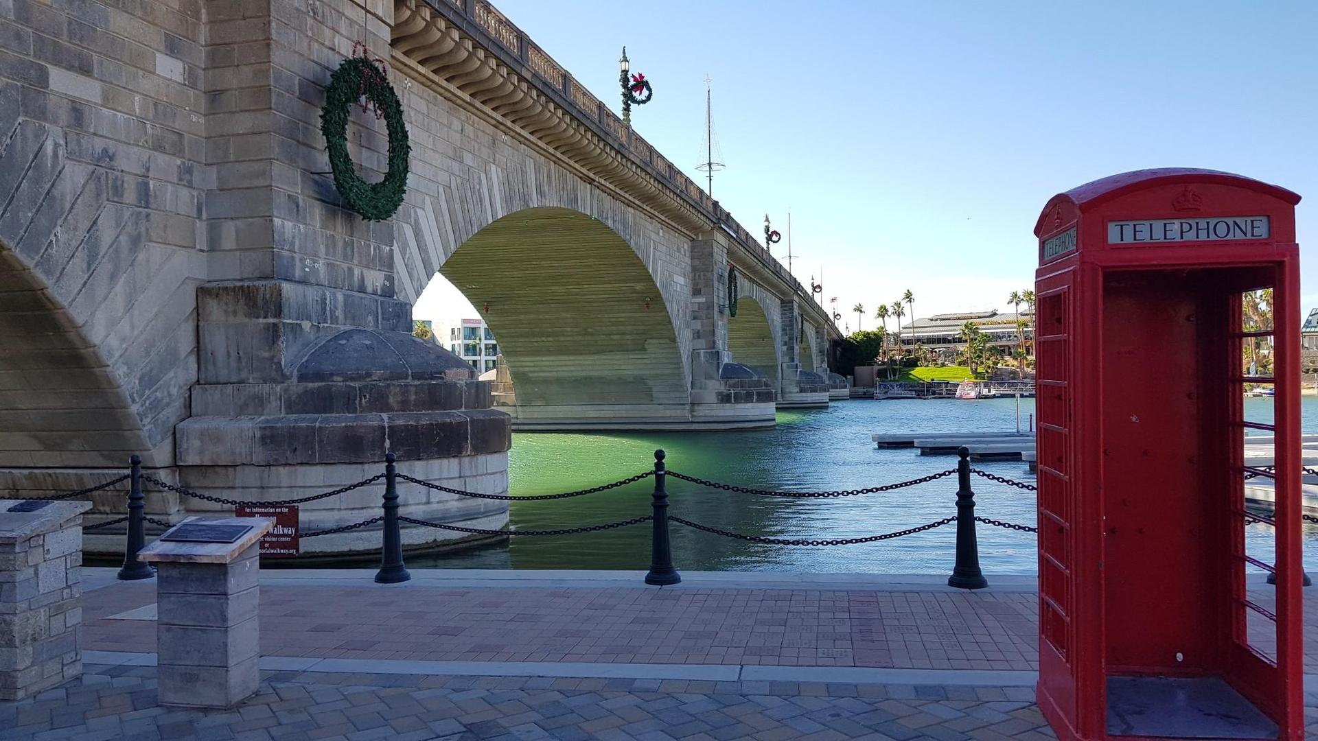 Stone bridge with a wreath and a red telephone booth by green water.