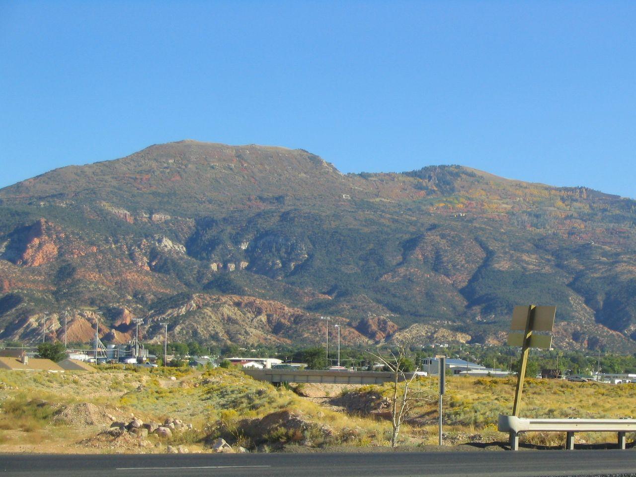 Expansive mountain range with arid foothills under a bright blue sky.