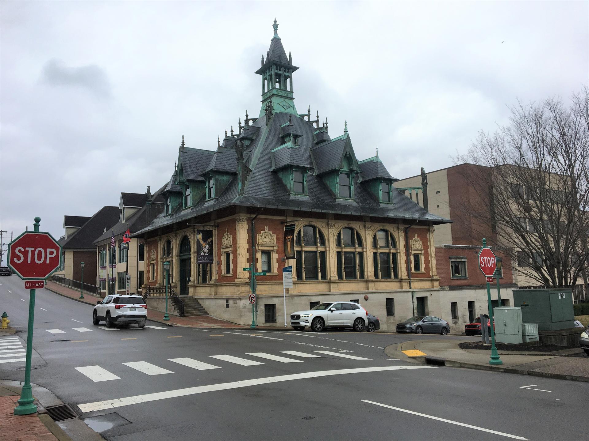 Ornate historic building on a city street corner under an overcast sky.