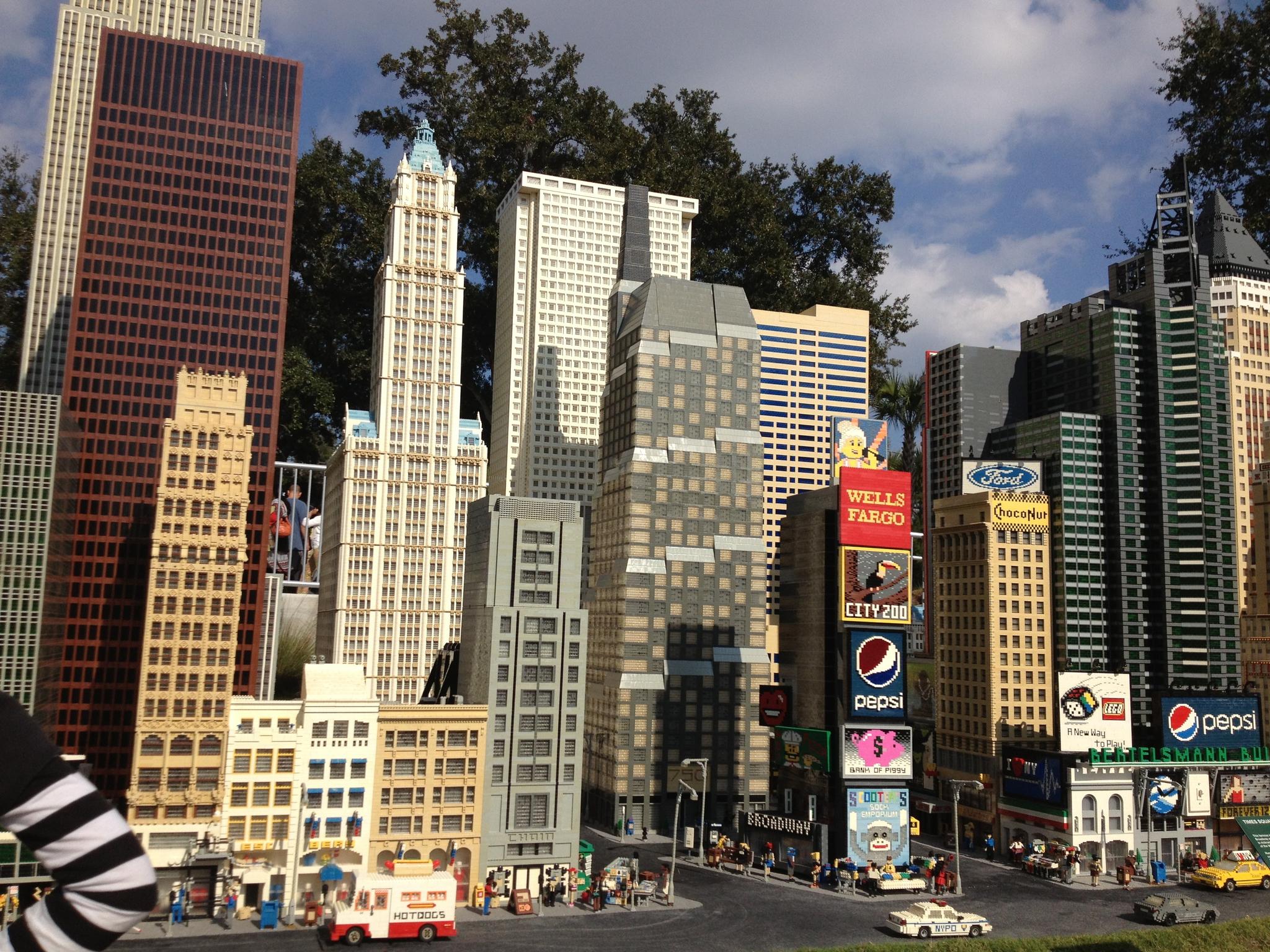 Miniature block city with tall buildings and street scene under bright daylight.