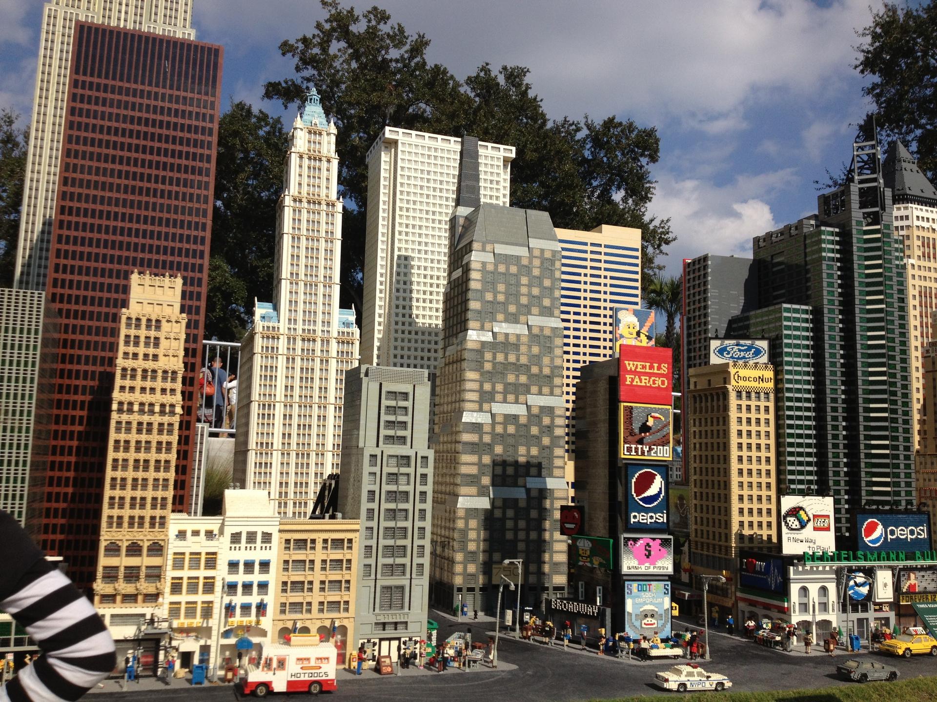 Miniature block city with tall buildings and street scene under bright daylight.