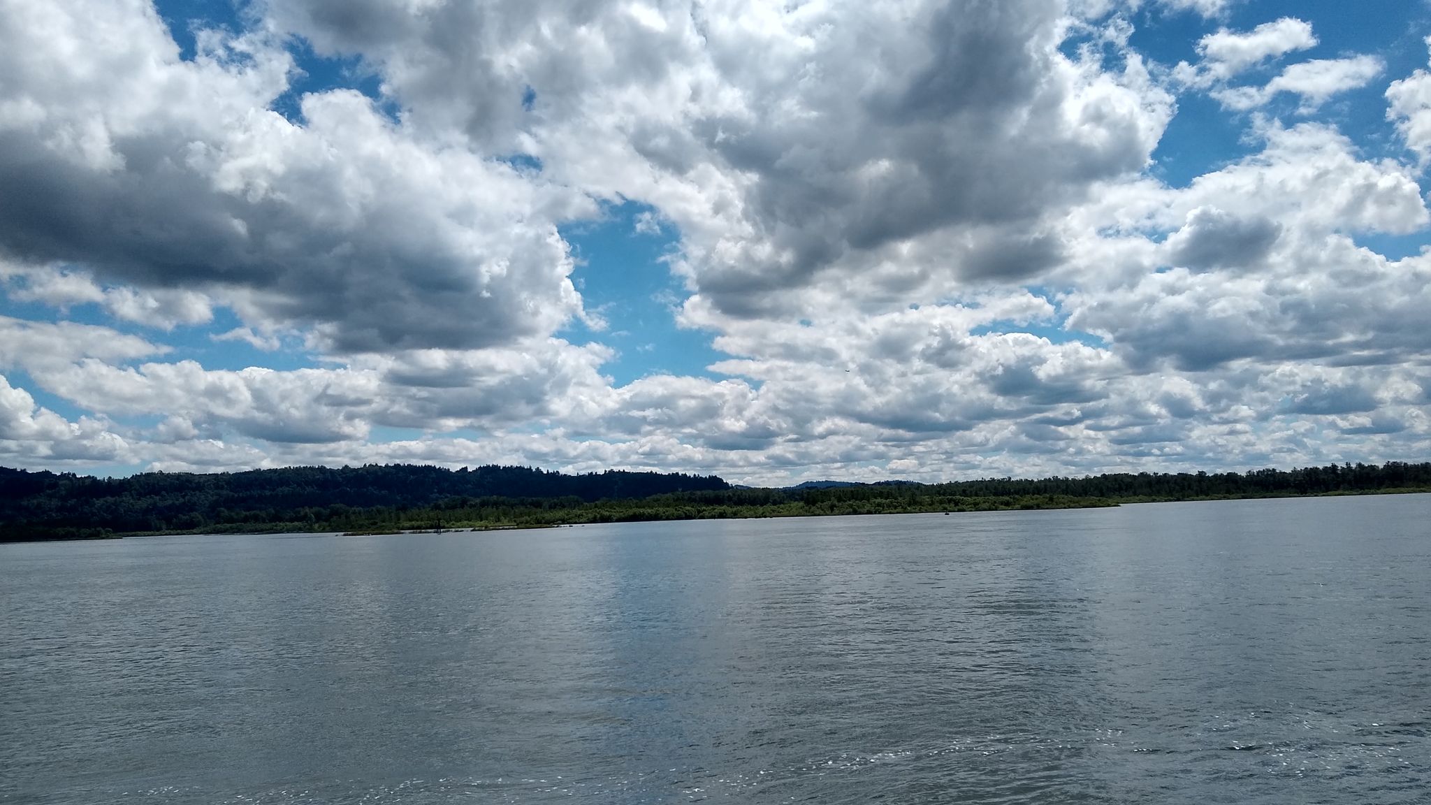 Wide river with forested banks under a dramatic cloudy sky. - Reflection Plaza – Washougal Waterfront Park loop from Washougal