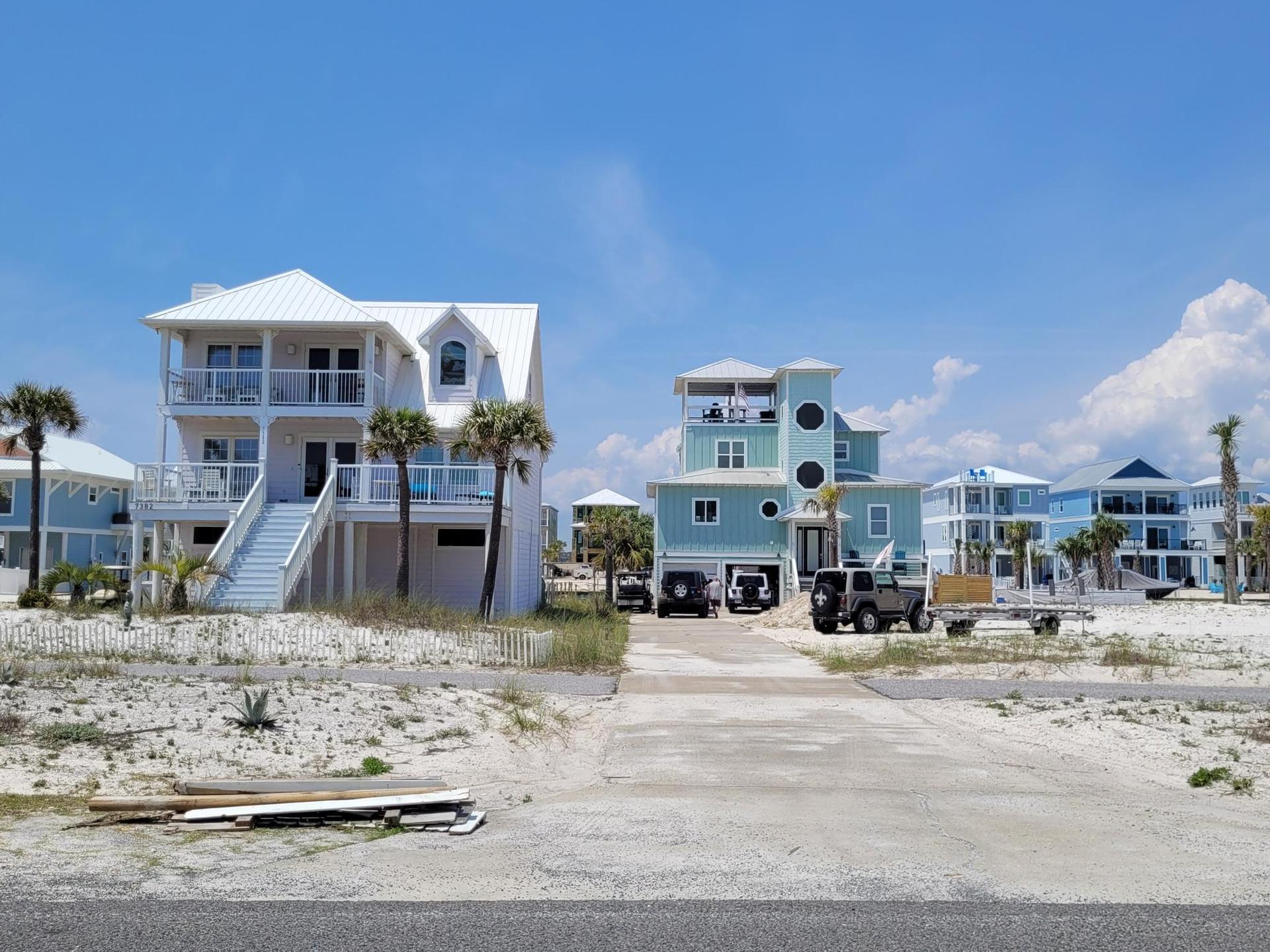 Brightly lit beach houses and vehicles on sandy ground under a clear sky.