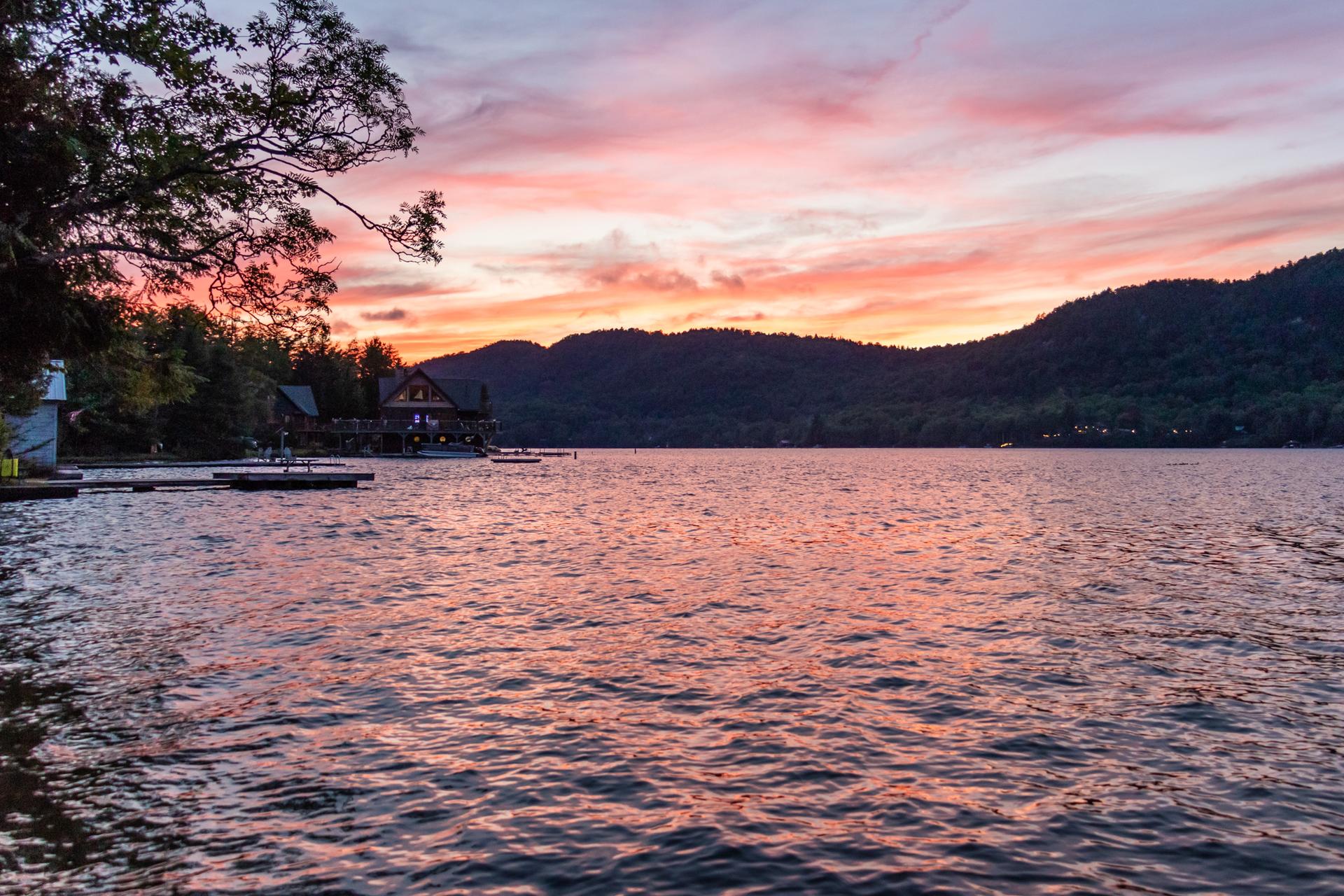 Lake at dusk with houses, docks, and a colorful sky.