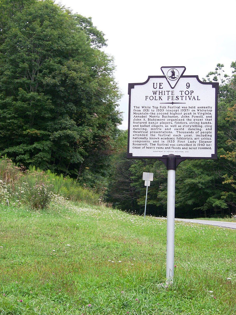 A historical marker sign stands beside a grassy field and green trees. - TransVirginia Bike Route