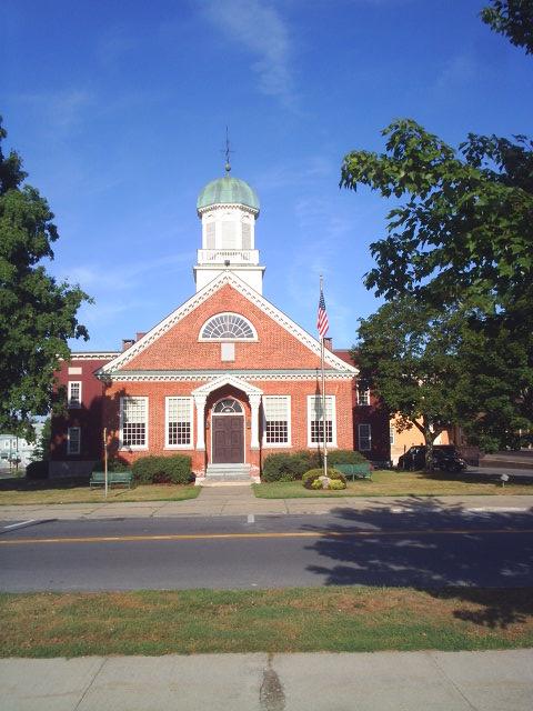 A red brick building with a white cupola under a clear blue sky.