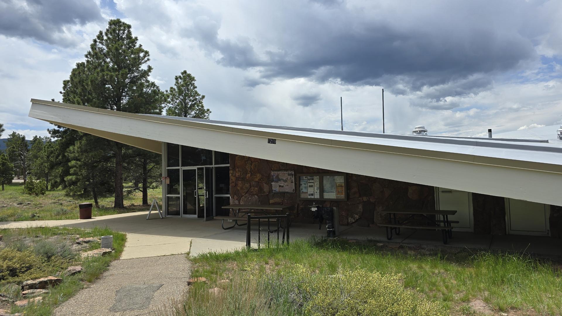 A modern building with a slanted roof and stone facade under cloudy skies.