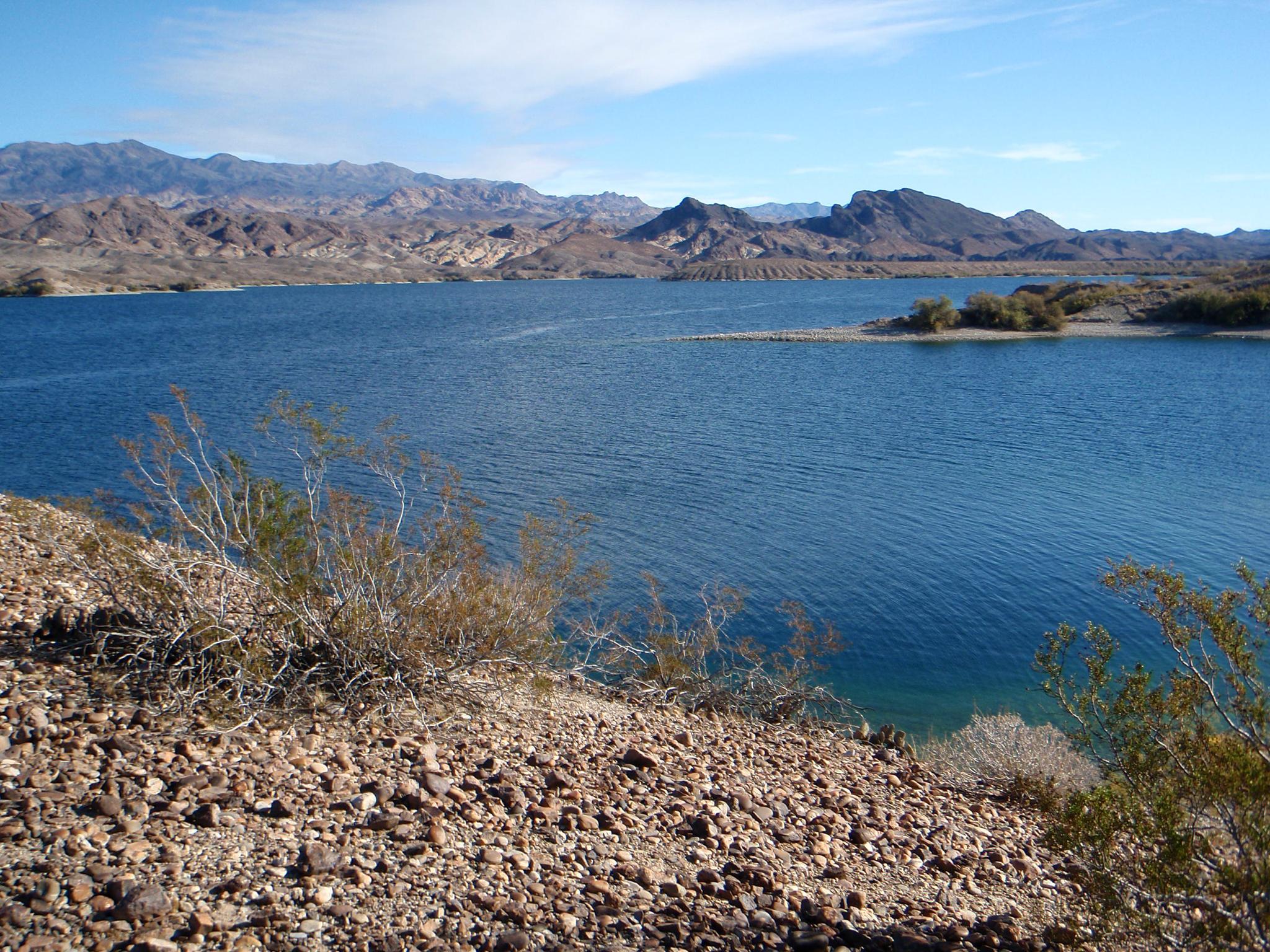 A vast blue lake with arid, rocky shores and distant mountains.