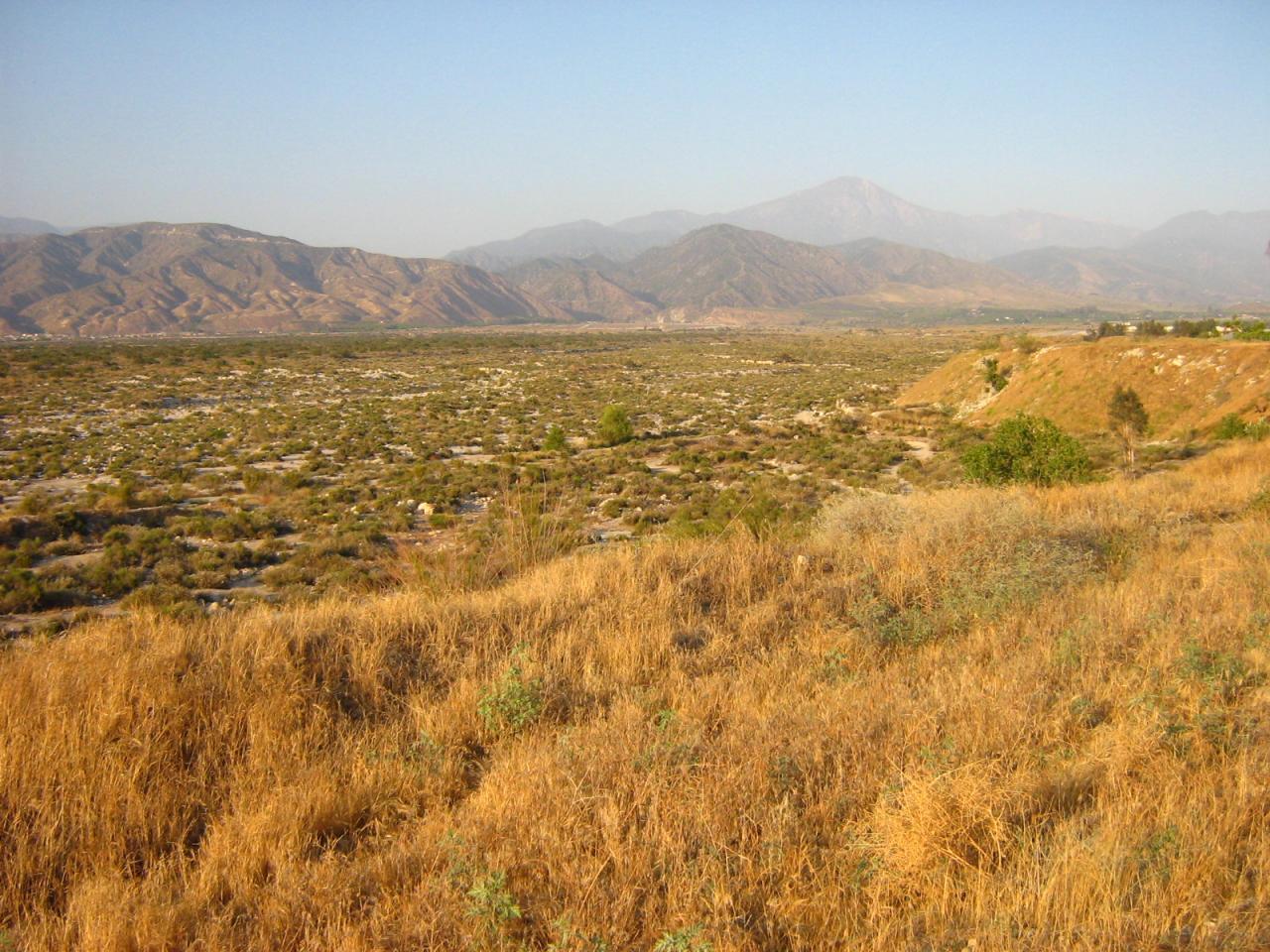 Expansive dry landscape with golden grass, rolling hills, and distant mountains.