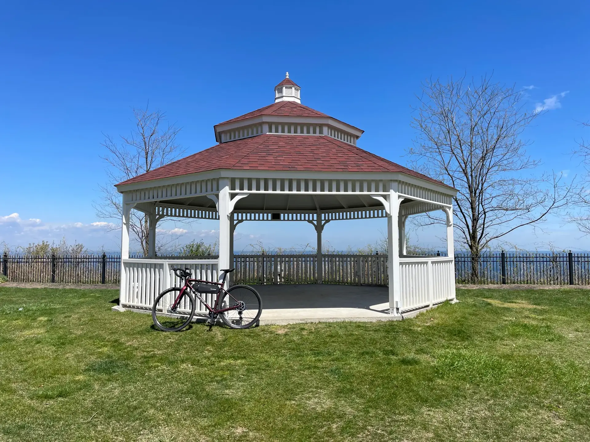 White gazebo with a red roof on a sunny day, a bicycle parked nearby.