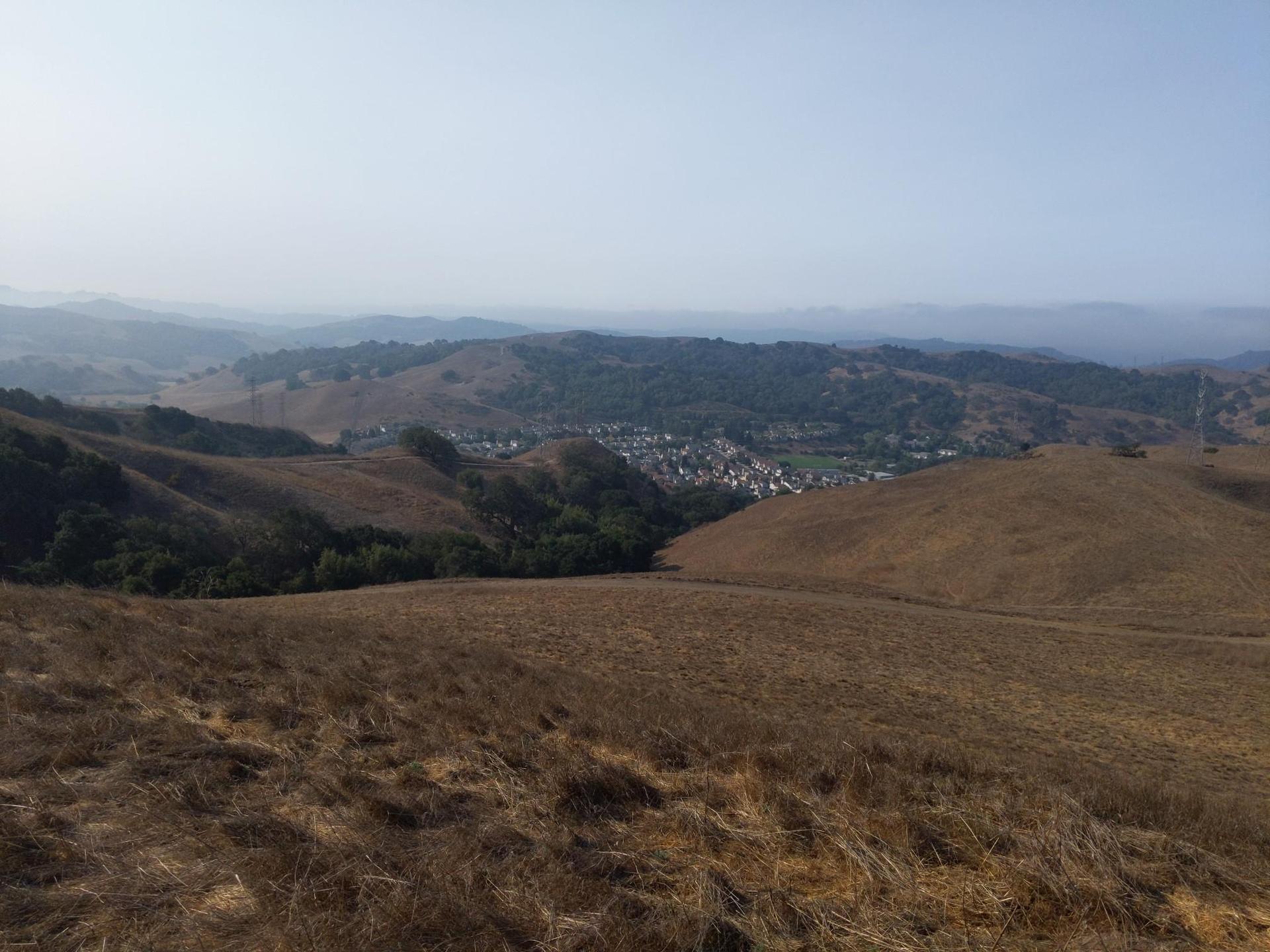Hazy panoramic view of dry hills overlooking a distant town.