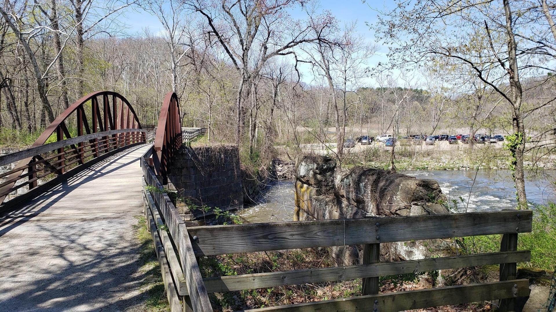 A sunny view of a pedestrian bridge next to a flowing river.