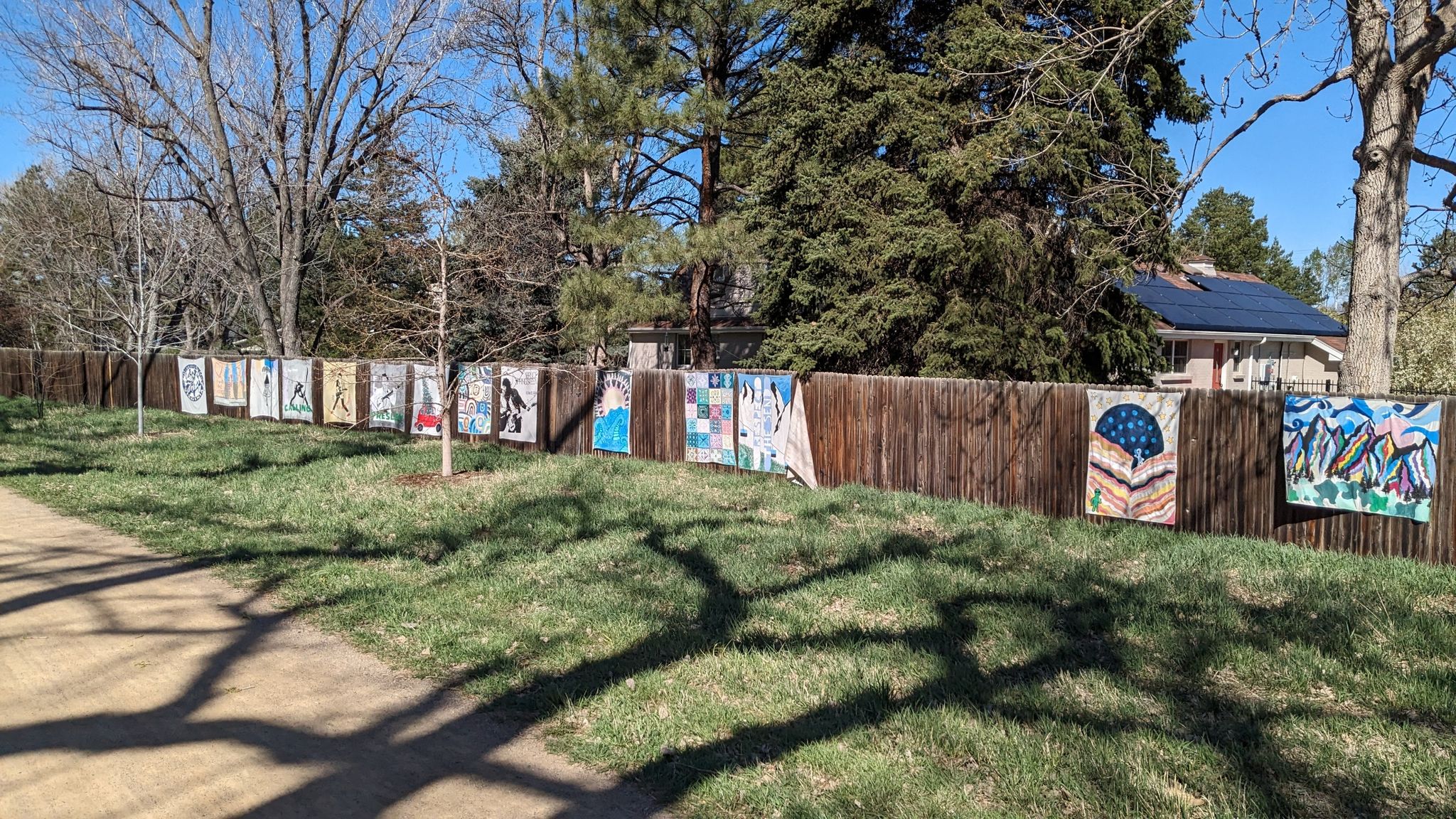 A long wooden fence adorned with colorful art panels under bright daylight. - Blackmer Lake – Sumac Hill Farm viewpoint loop from Yale