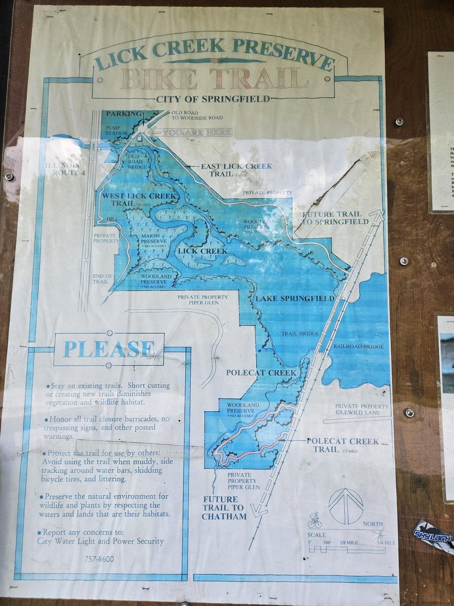 A weathered blue and white map displays bike trails and a preserve outdoors.