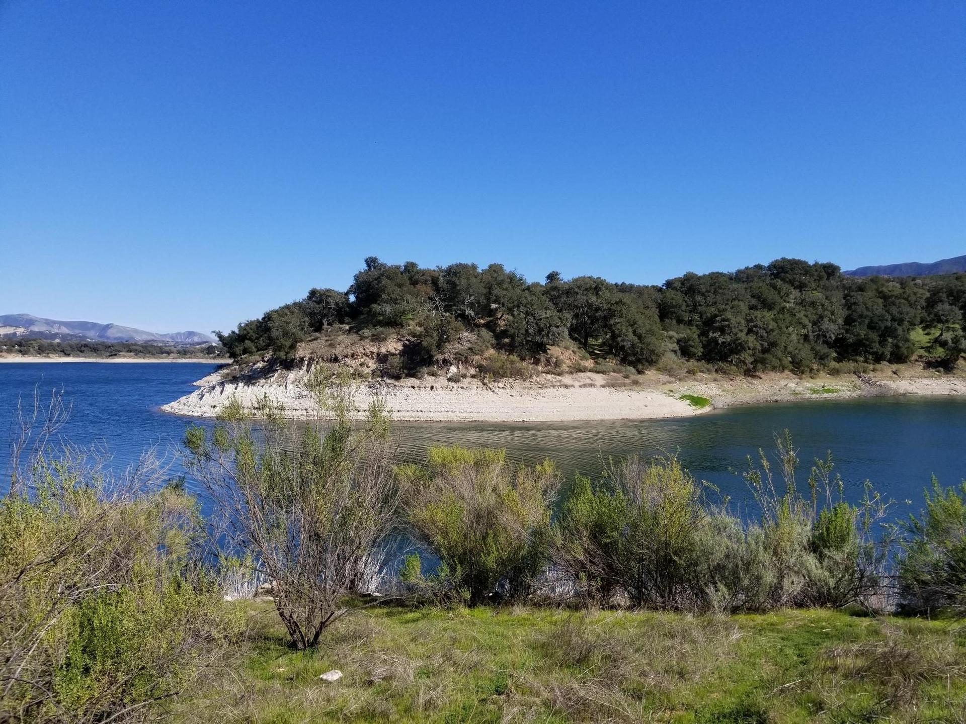 Bright sunny day over a blue lake with a tree-covered peninsula.